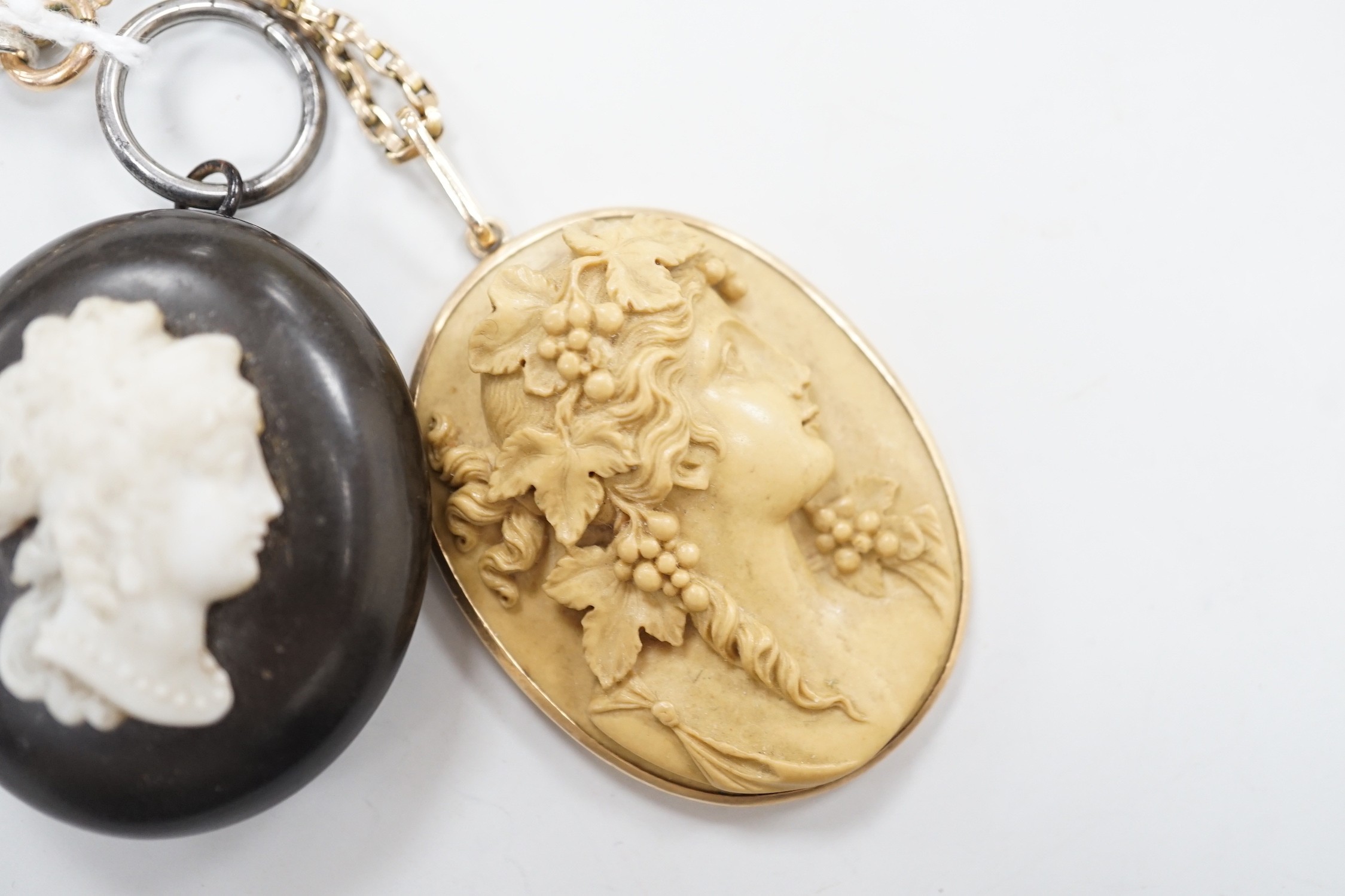 A late Victorian yellow metal mounted oval lava pendant, carved with the bust of a lady to sinister, 47mm, on a 9ct chain, together with phenolic oval locket.